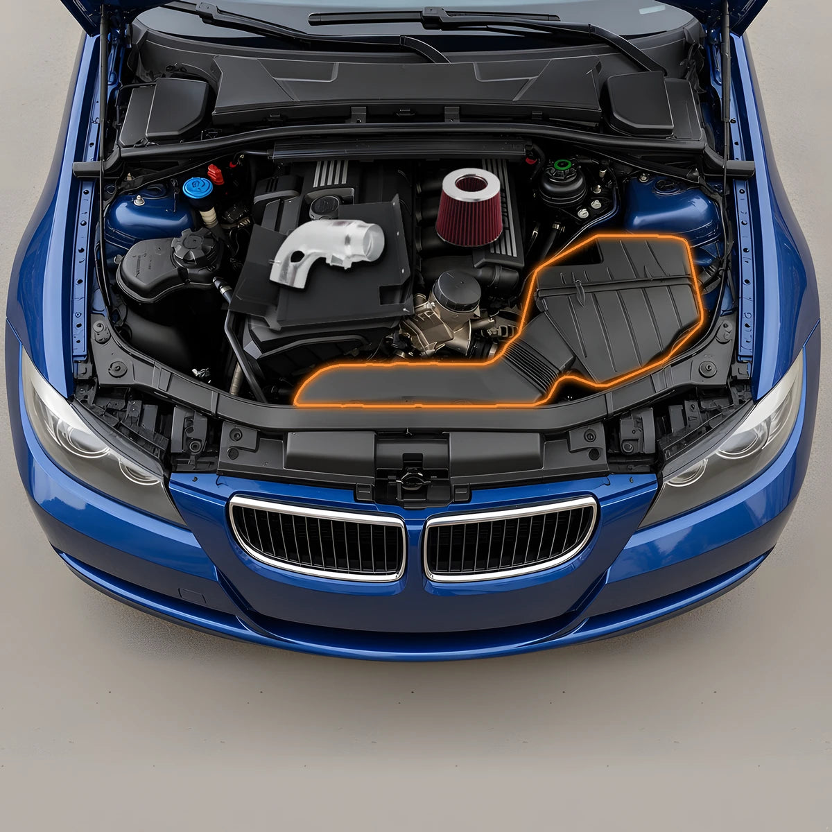 BMW 328i E90 3.0L inline-6 engine bay with the cold air intake pipe, filter and heat shield resting on the engine, and the stock airbox and intake duct it replaces outlined in orange