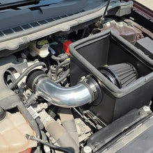 Car engine with a black air filter housing and silver intake pipe.