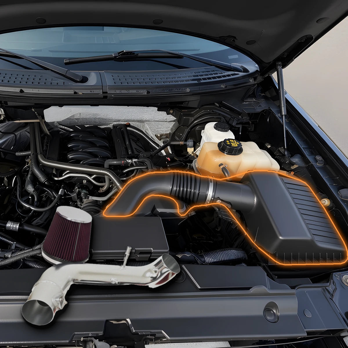 Cold air intake laid over a 2011-2014 Ford F-150 5.0L engine bay with the stock airbox highlighted