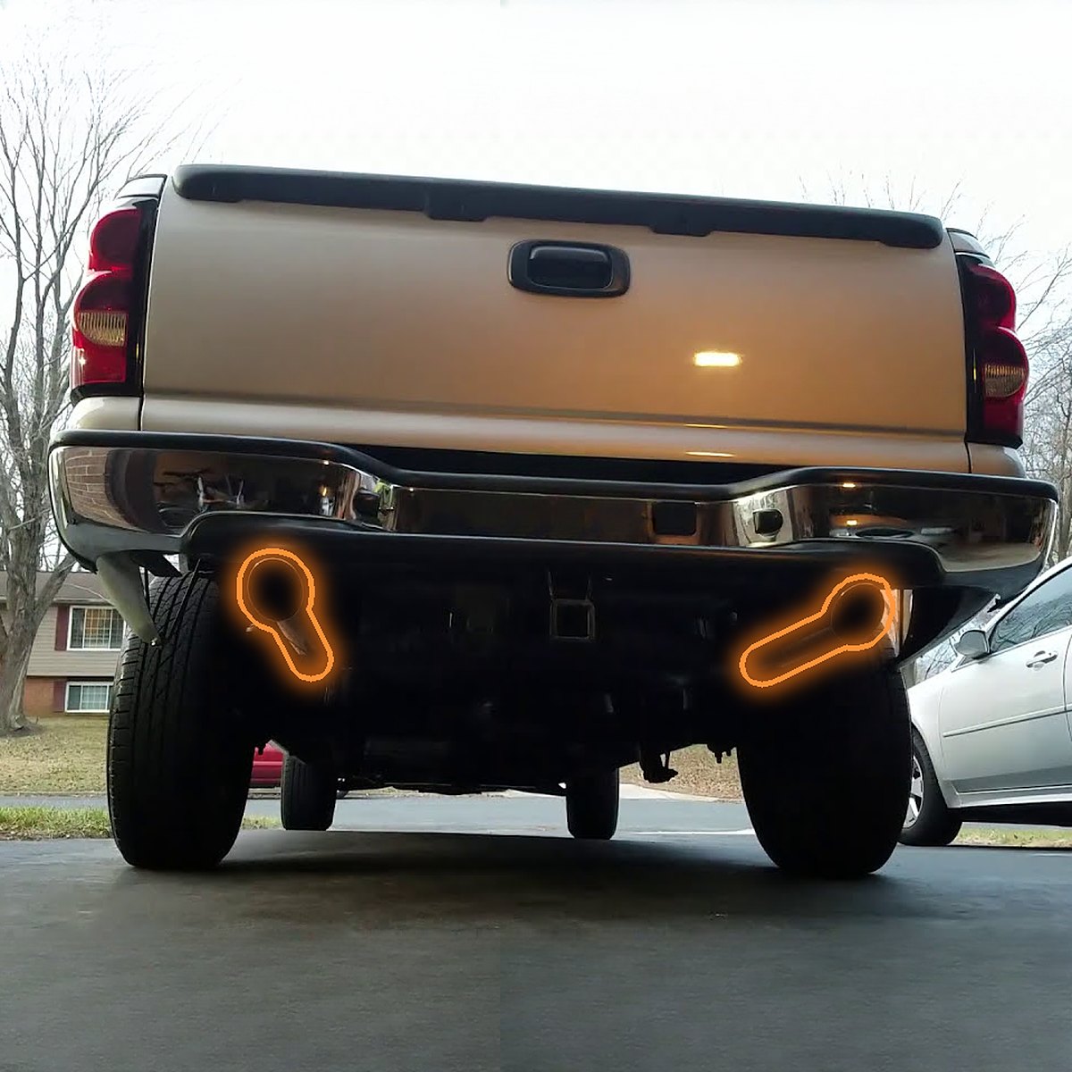 Rear view of a GMT800 pickup with the dual rear exhaust exits behind each rear tire highlighted