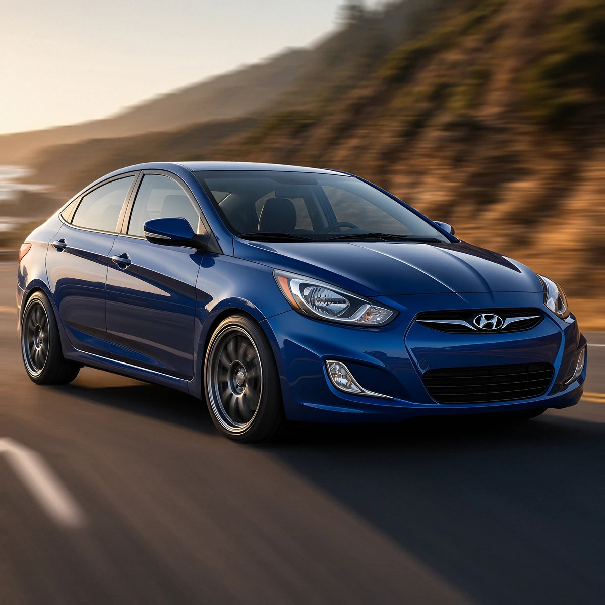 Blue 2012-2013 Hyundai Accent sedan with sport wheels driving fast on a coastal road - cold air intake for 1.6L engine