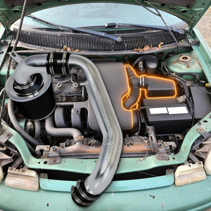 1998 Neon 2.0L SOHC engine bay with the factory air box and intake duct highlighted and the chrome intake kit that replaces them