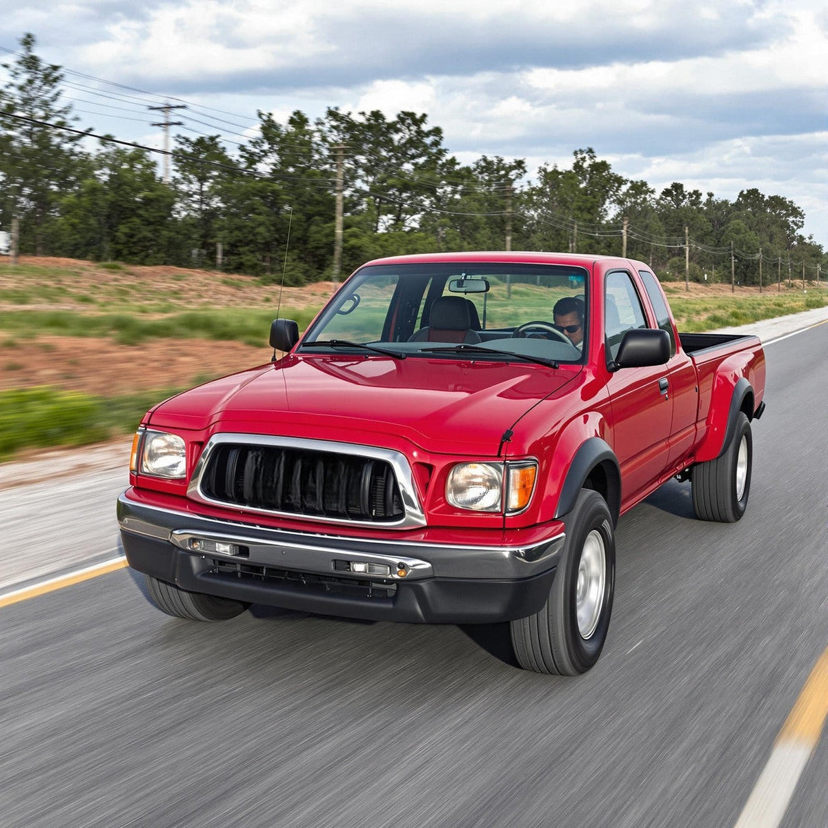Red Toyota Tacoma pickup driving fast on the highway