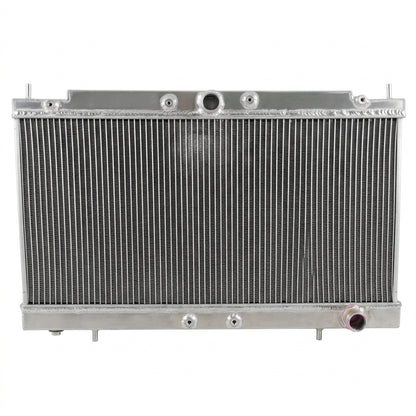 A silver aluminum automotive radiator with a ribbed metal core and mounting brackets, photographed against a plain light gray background.